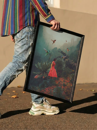 Person holding framed "20 Seconds Before the Rain - Frank Moth" print, featuring a woman in red in a lush forest.