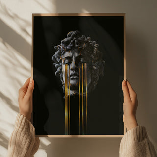 Hands holding an art print of a Medusa sculpture with golden tears, on a black background.
