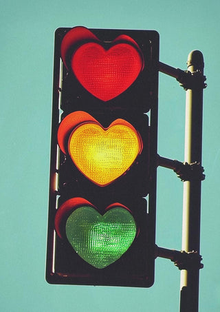 Traffic light with heart-shaped red, yellow, and green signals against a blue sky for Traffic Light In Love.