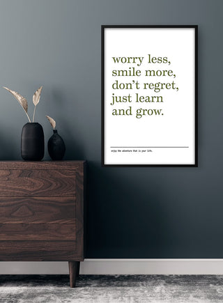 Minimalist "Worry Less Smile More" poster on a dark wall above a wooden dresser, modern home decor style.
