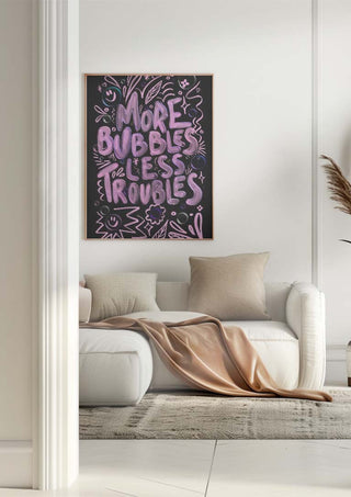 Framed "More Bubbles Less Troubles" wall art above a cozy white sofa in a modern living room.