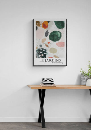 Le Jardin Du Luxembourg 02 abstract art print in black frame, displayed above a wooden table with decor.
