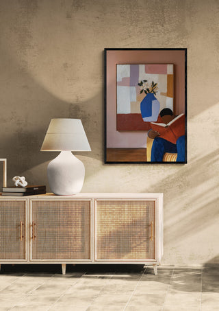 Framed print of "The Reader" by David Wolf hanging above a modern sideboard in a stylish living room.