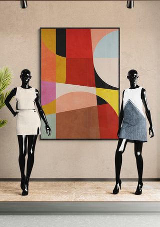 Two mannequins in minimalist dresses stand before a bold geometric abstract painting on a neutral wall.