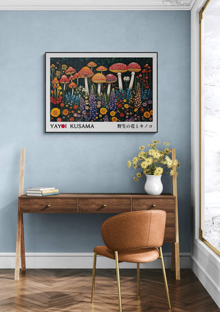 Framed Yayoi Kusama "Infinity" mushroom art print hanging above a wooden desk with books and flowers.