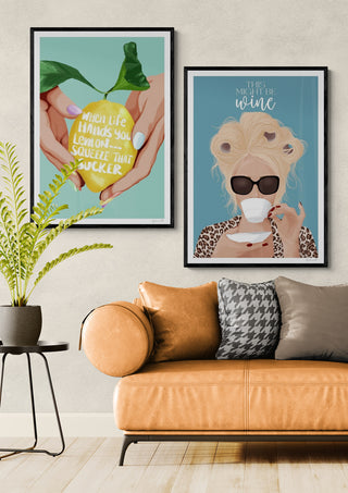 Framed "Squeeze That Lemon - ByKammille" print displayed above a tan sofa in a modern living room setting.