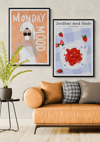 Framed poster of strawberries and cream by ByKammille on wall above tan sofa, Strawberry Denmark product page.