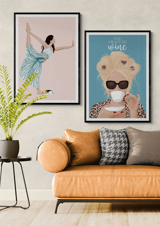Framed Yoga - ByKammille artwork displayed above a tan sofa and green plant in a modern living room.