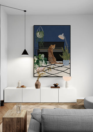 Framed print of "Cheetah playing piano - Sarah Manovski" hanging in a modern living room above white cabinet.