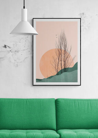 Framed "Sunset Memories" art by Boris Draschoff above a green sofa, sun and tree design in soft colors.