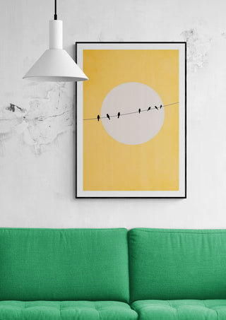 Framed Chirping and Chilling print by Boris Draschoff above a green sofa in a modern living room.
