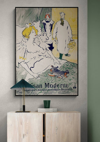 Framed "Artisan Moderne" poster by Henri de Toulouse-Lautrec displayed above a light wood cabinet in a modern room.